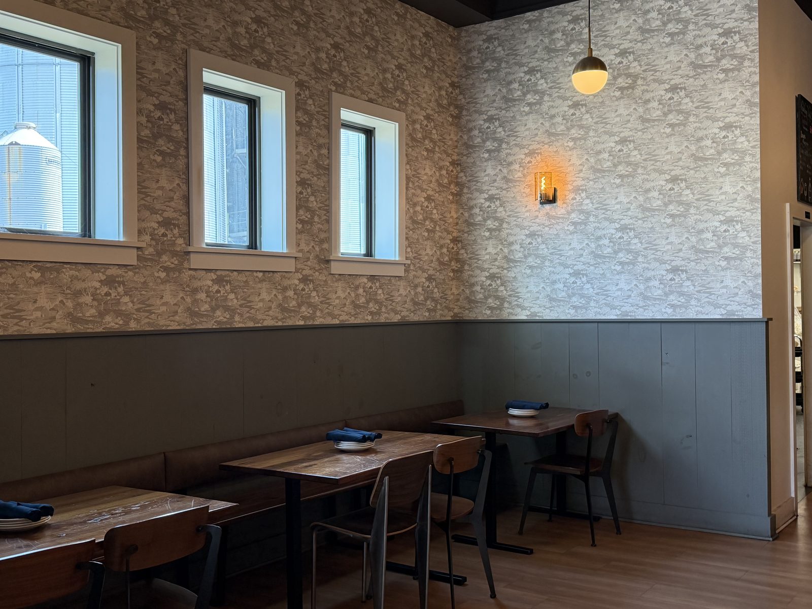 Harvest Granville corner banquette with woodland wallpaper and windows overlooking a grain silo